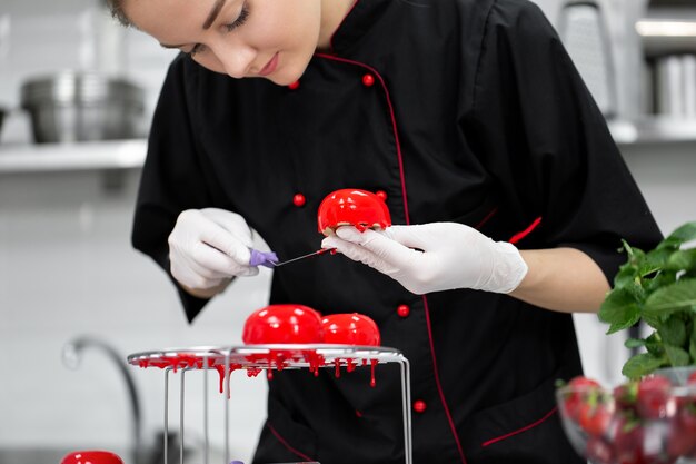 O chef pasteleiro cobre o bolo de mousse com um esmalte de espelho.