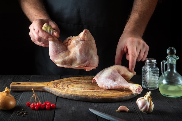 O chef prepara pernas de frango cru na cozinha do restaurante perna de frango na mão do cozinheiro