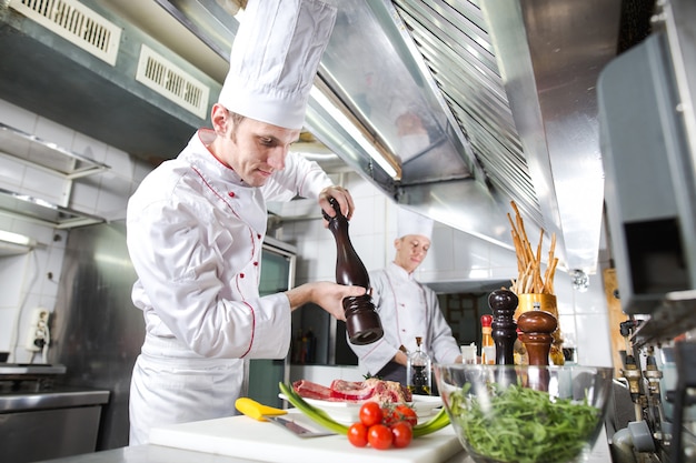 O chef prepara um prato na cozinha do restoran.