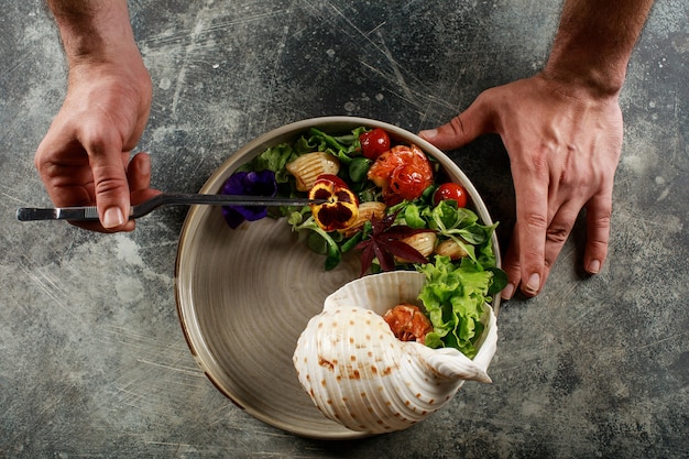 Foto o chef prepara uma salada de frutos do mar e vegetais