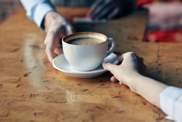 O chef serve ao cliente uma xícara de café com um pires na mesa e uma bebida do restaurante