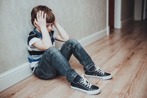 Foto o choro do menino cobriu o rosto com as mãos. criança estressada. violência doméstica familiar e violência do conceito de agressão. conceito de bullying, depressão, estresse ou frustração