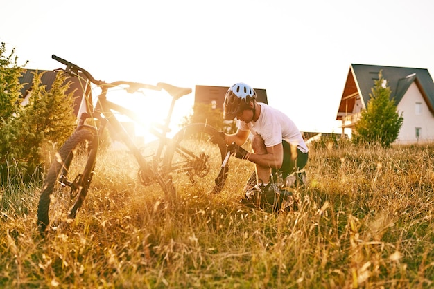 O ciclista repara e muda o pneu de sua bicicleta para a montanha ao pôr do sol reparo de pneus de bicicleta foco seletivo