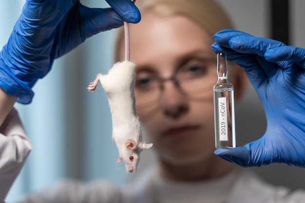 O cientista segura um rato branco pela cauda na frente de seu rosto. E também o assistente de laboratório segura uma ampola de vidro com uma preparação especial. Ciência e medicina.