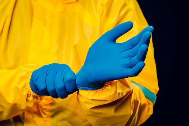 Foto o cientista usa um traje de descontaminação amarelo e usa luvas de borracha azuis para proteger sua pele.