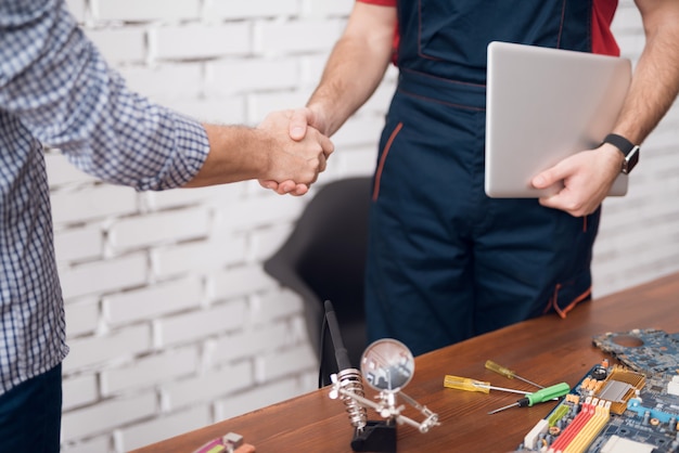 O cliente aperta a mão do reparador do computador.