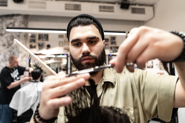 O cliente corta o cabelo em uma barbearia. Cuidado do cabelo dos homens. Corte de cabelo com tesoura