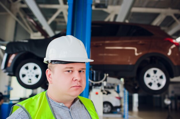 O cliente olha o trabalho em uma roda de oficina de carro sob o carro em serviço