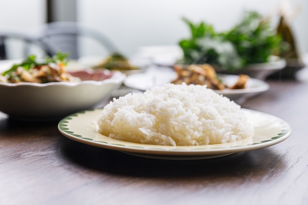 Foto o close-up cozinhou o arroz em um prato servido com fundo dos alimentos do borrão.