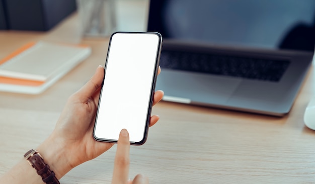 O close up da mão da jovem mulher que guarda o smartphone na tabela e na tela é vazio, conceito social da rede.