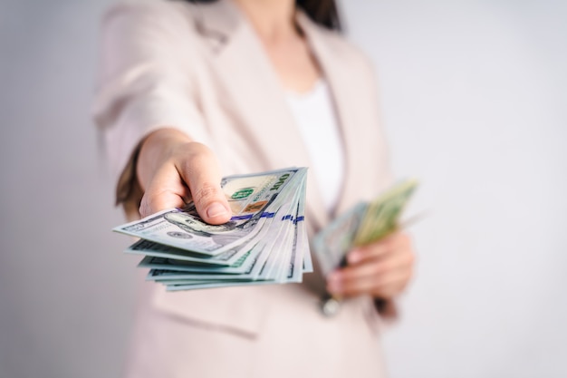 O close up da mulher de negócio entrega propor dinheiro nos notas de dólar no branco. Conceito de dinheiro.