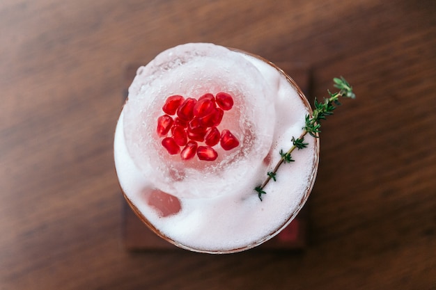 O cocktail cor-de-rosa da romã serviu com as sementes na bacia e nos alecrins da forma do gelo.