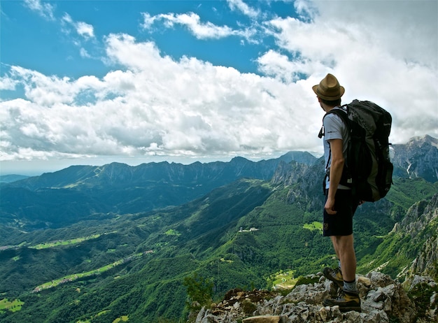 O comprimento total de um homem de pé na montanha contra o céu