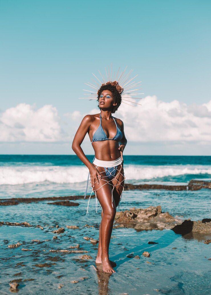 Foto o comprimento total de uma jovem de pé na praia contra o céu