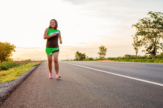 Foto o comprimento total de uma mulher a correr na estrada