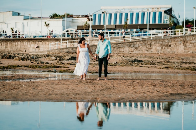 Foto o comprimento total do casal de pé na praia contra o céu