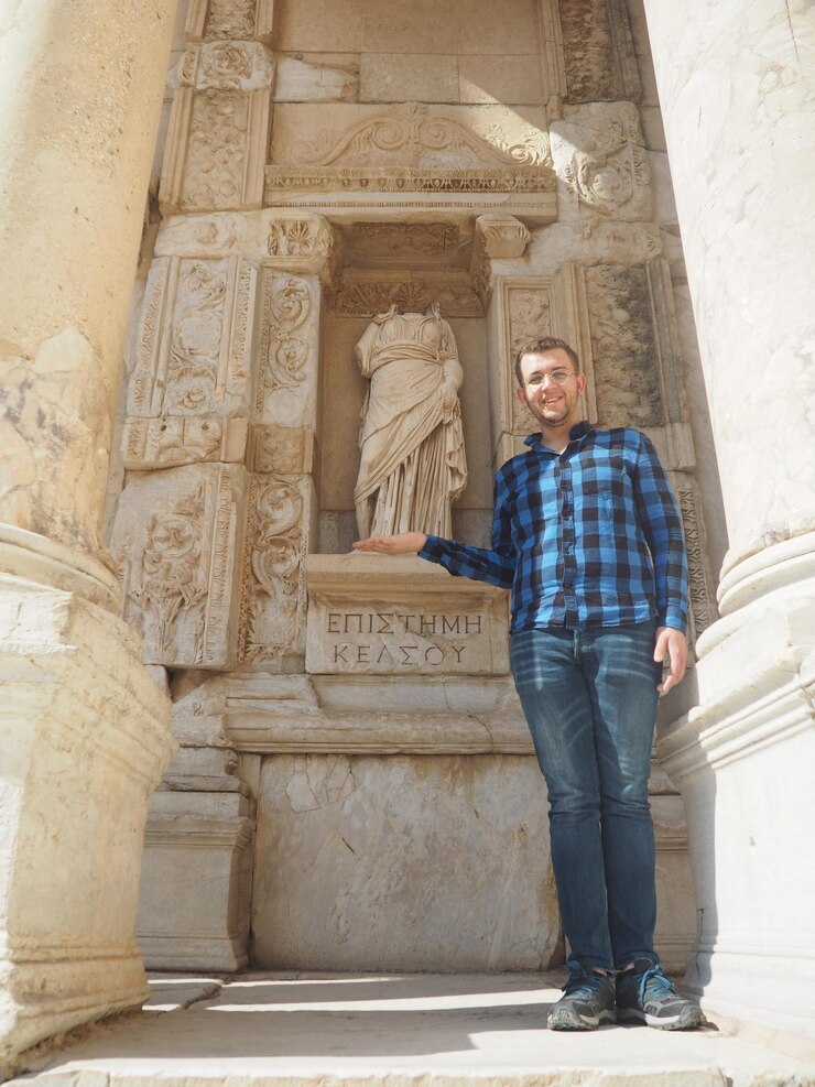 Foto o comprimento total do homem fazendo gestos enquanto está de pé junto à estátua