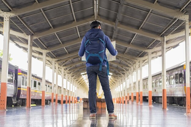 Foto o comprimento total do mapa de leitura do turista enquanto está de pé na plataforma da estação ferroviária