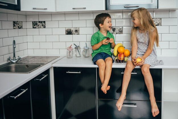 O conceito de alimentação saudável. crianças engraçadas com frutas na cozinha