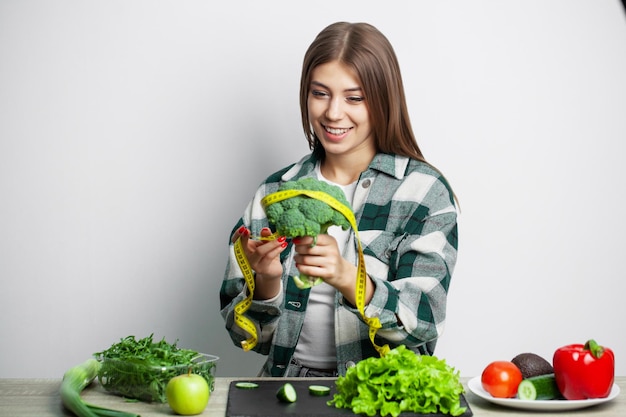 O conceito de alimentação saudável e dieta garota segurando vegetais na parede branca de fundo.