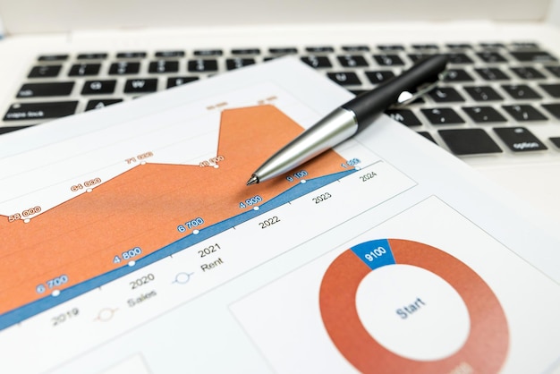 O conceito de análise closeup de gráficos de investimento com laptop e caneta na mesa contabilidade