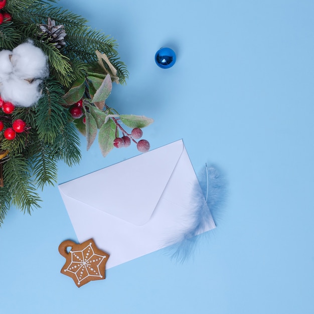 O conceito de ano novo com uma árvore de natal e decorações de natal, um envelope branco para uma carta em um fundo azul está próximo.