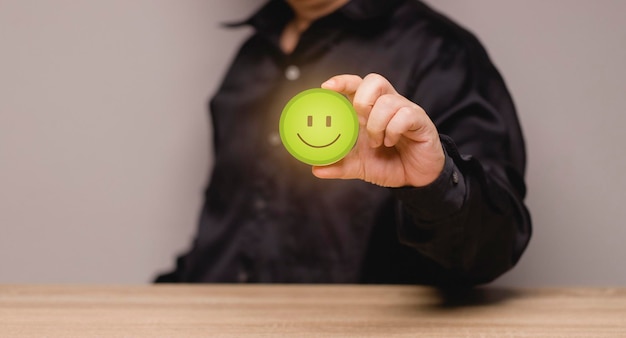 O conceito de avaliação de satisfação do serviço homem segurando o ícone de carinha verde Avaliado para maior satisfação apresentando satisfação Questionário da pesquisa