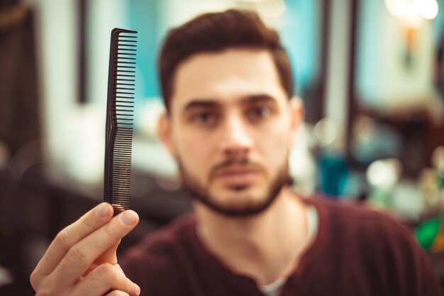 O conceito de beleza. Um homem segurando um pente na mão estendida. Foco suave.