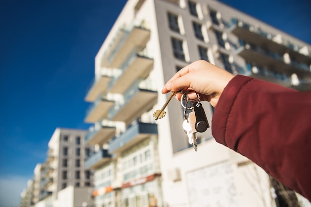 O conceito de comprar um apartamento novo. a mão da mulher segura as chaves de um novo apartamento.