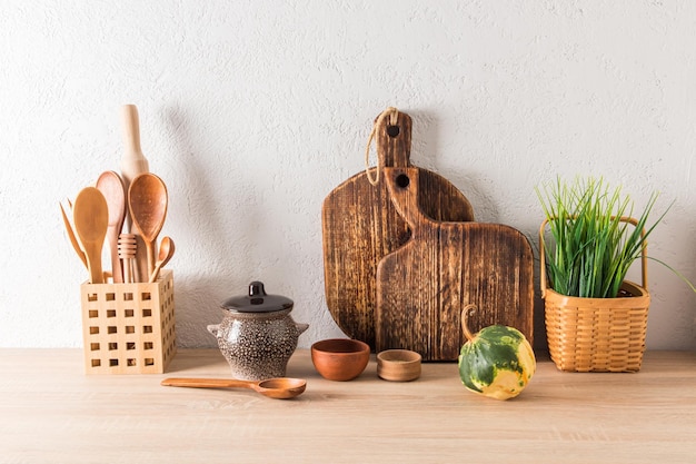 O conceito de decoração da cozinha doméstica em uma casa de campo, utensílios de madeira, cerâmica e pratos cerâmicos, planta na cesta zero desperdício