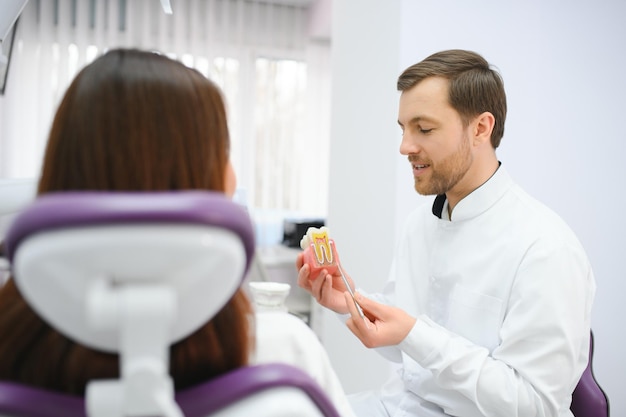 O conceito de diagnóstico e tratamento de doenças dentárias O médico mostra um modelo de dente doente
