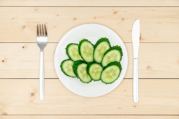 O conceito de dieta e alimentação saudável Fatias de pepino verde fresco em um prato branco