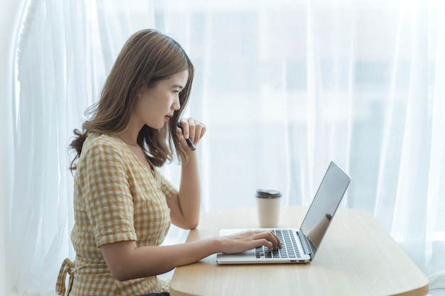 O conceito de empreendedor é uma jovem empresária digitando em um laptop para responder a e-mails de seus clientes.