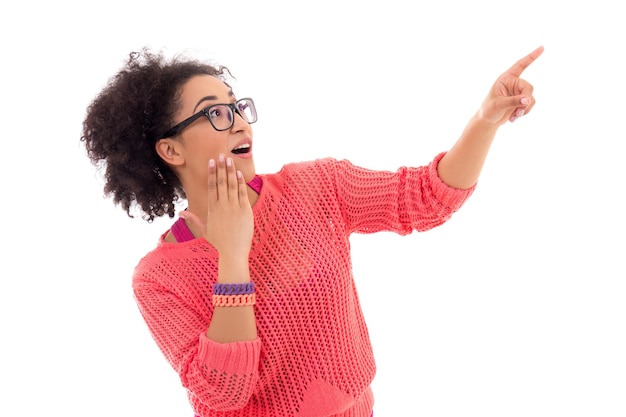 O conceito de fofoca empolgou uma adolescente afro-americana em rosa apontando para algo isolado no fundo branco