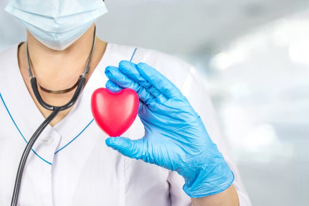 O conceito de medicina e seguro saúde. Perto da mão do médico segurando um coração vermelho no escritório do hospital. Conceito de cuidados de saúde e paciente, falha e doenças. Exame de saúde anual.