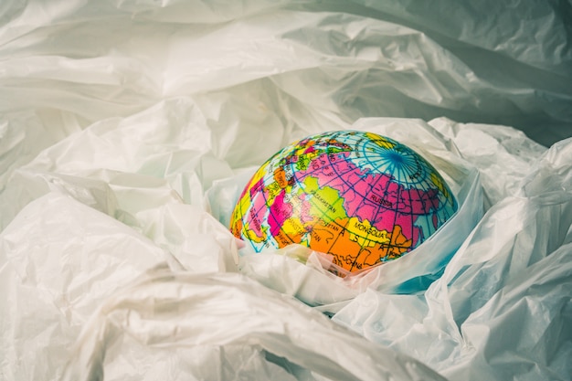 O conceito de redução do uso de sacolas plásticas: globos modelados são afundados em muitas sacolas plásticas brancas. Os sacos de plástico estão prestes a transbordar o mundo.