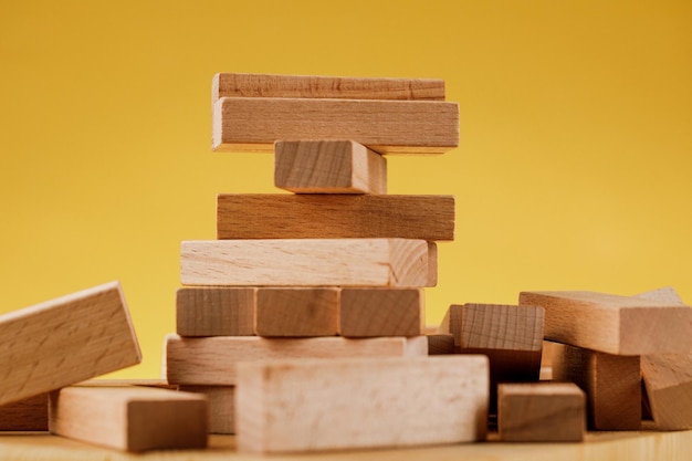 O conceito de risco empresarial com o modelo jenga Blocos de madeira em fundo amarelo