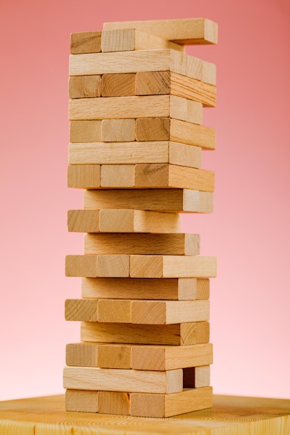 O conceito de risco empresarial com o modelo jenga. Blocos de madeira em um fundo rosa.