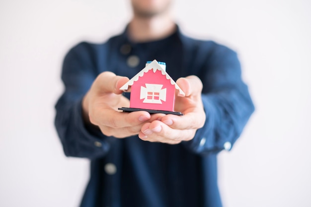 O conceito de seguro de propriedade, as mãos segurando um pequeno brinquedo de casa e proteger o imóvel