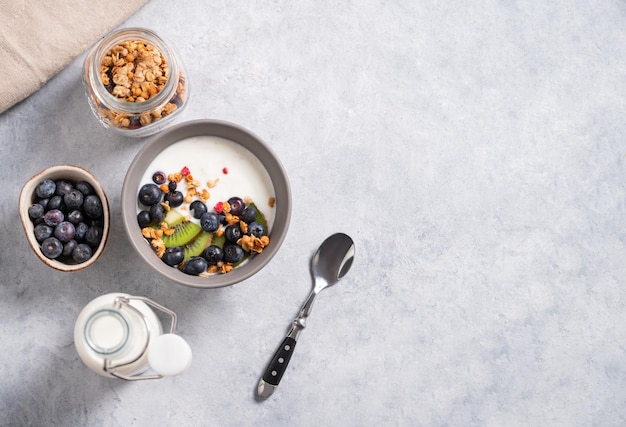 O conceito de um café da manhã saudável de granola de iogurte vegetariano e frutas frescas em um fundo azul vista superior e espaço de cópia