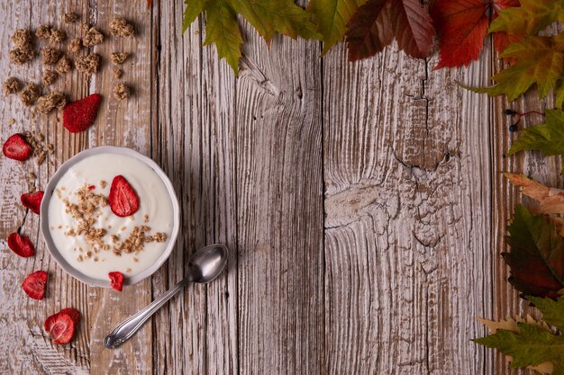 O conceito de um iogurte natural saudável de café da manhã de outono com morangos desidratados e muesli