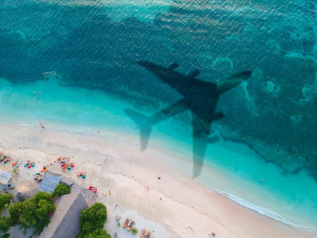 O conceito de viagens e viagens aéreas. vista superior da costa do oceano, com a sombra na água da decolagem do avião.