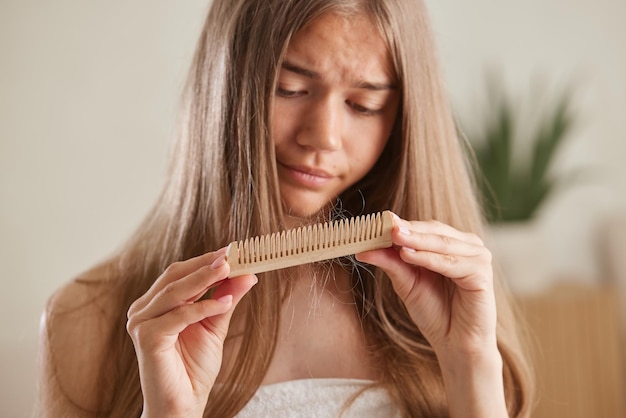 O conceito do problema da perda de cabelo Mulher asiática chocada olha para muito cabelo perdido na mão e penteia