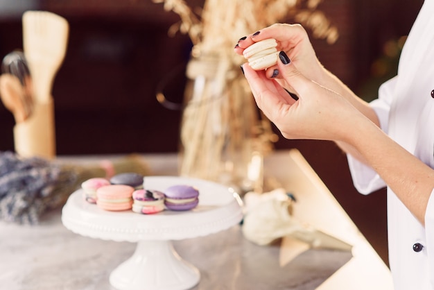 O confeiteiro une as partes dos macarons usando um creme. Feche as mãos do padeiro fazendo macarons.