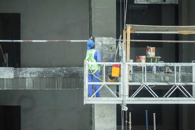 O construtor em um guindaste suspenso está pintando. Terminando o trabalho