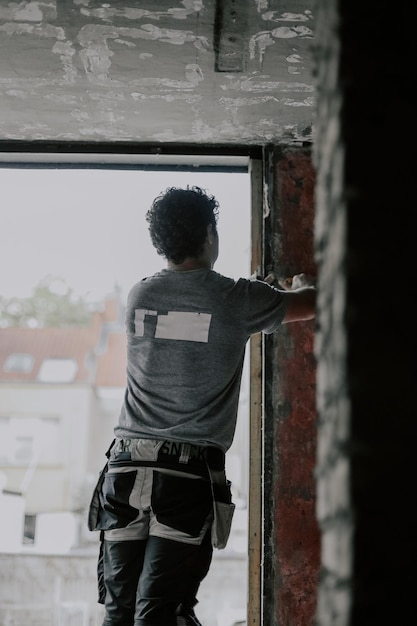 O construtor masculino caucasiano limpa a abertura da janela