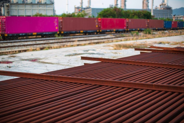 O contêiner frontal no trem e no caminho ferroviário está esperando para enviar ao porto esta imagem para o conceito logístico de importação e exportação cena da planta e torre da refinaria de petróleo do tanque