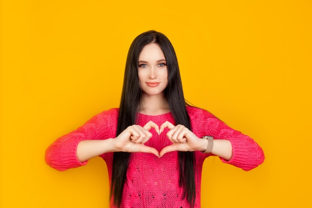 O coração é feito de mãos, feito por uma garota em uma parede amarela brilhante, com um suéter rosa. O conceito é feito com amor, dar amor, emoção de confiança e simpatia