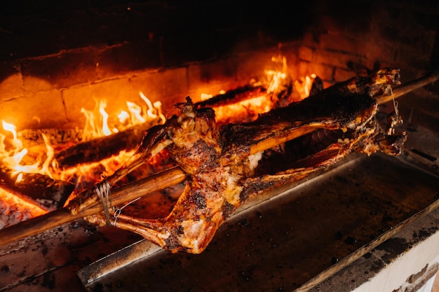 O cordeiro é cozido inteiramente no espeto no fogo Cozinhar