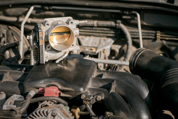 Foto o corpo de acelerador eletrônico e a capa inferior do carro moderno com motor oposto no fundo manutenção do motor tecnologia industrial